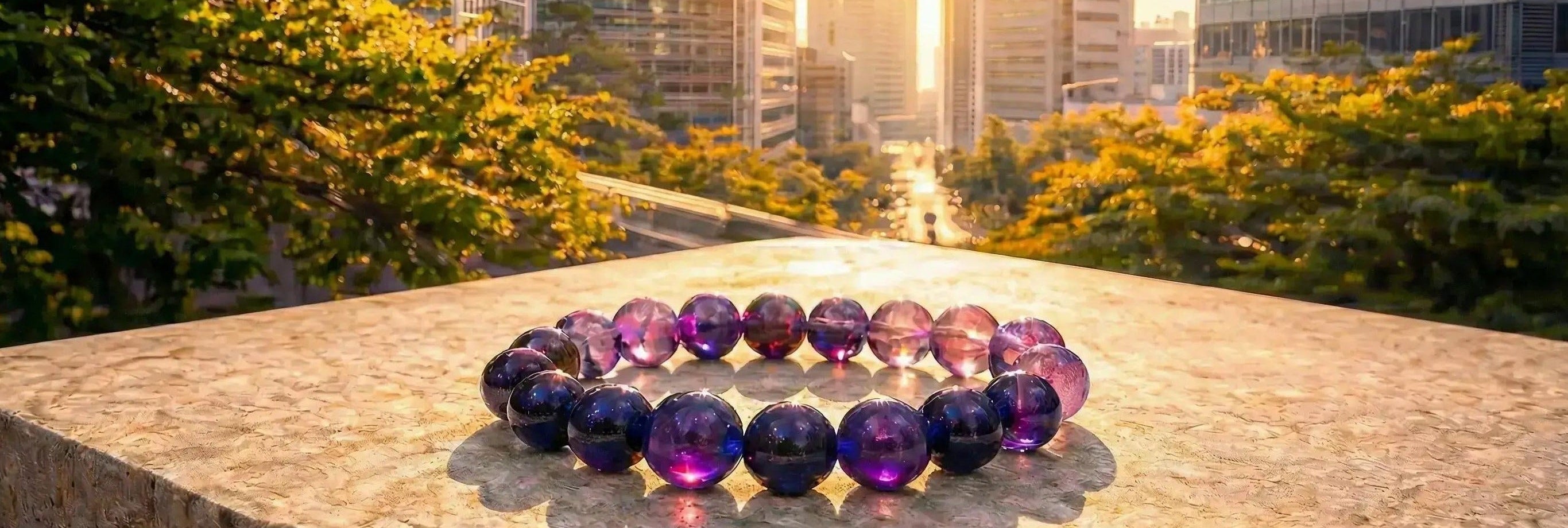 A luxury handmade Amethyst healing crystal bracelet featuring high-quality deep purple gemstone beads, displayed on a stone surface with a golden hour city skyline background for a modern spiritual lifestyle
